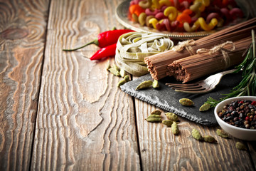 Raw pasta in the composition on the table with items for cooking