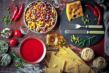 Raw pasta in the composition on the table with items for cooking