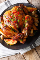 delicious whole grilled chicken with fried mushrooms and potatoes close-up on a plate. vertical