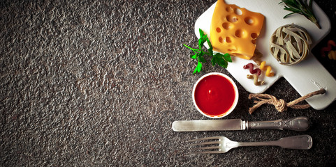 Raw pasta in the composition on the table with items for cooking