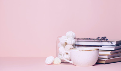 Close up of two cups and a book on pink background. Copy space for your text or design