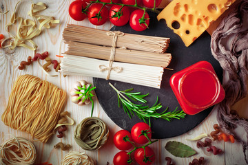 Raw pasta in the composition on the table with items for cooking