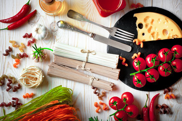 Raw pasta in the composition on the table with items for cooking