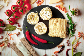 Raw pasta in the composition on the table with items for cooking