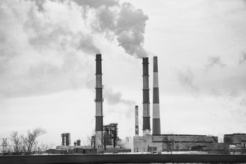 Smoking chimneys of the plant. Fuming chimney of a factory. Black and white photo