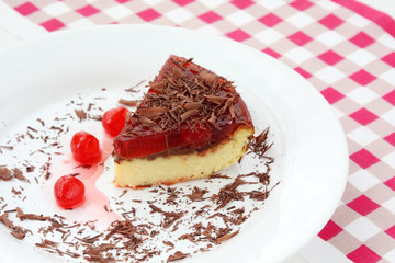 served on white plate slice of delicious cherry cheese cake with cherry topping and decorated with chocolate