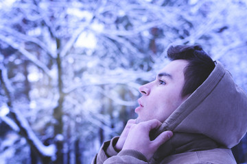 A young man walks in the woods in winter. Cold, frost, snow, winter.