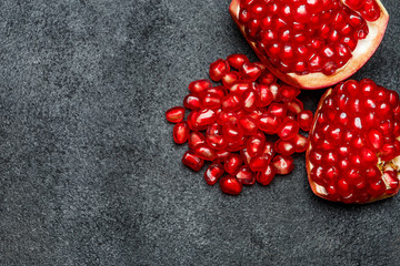 Pomegranate and seeds close-up on dark concrete background