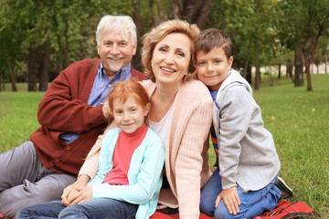 Happy senior couple with grandchildren in park