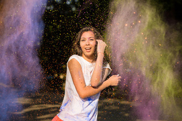Happy asian woman with long hair posing in a cloud of Holi paint