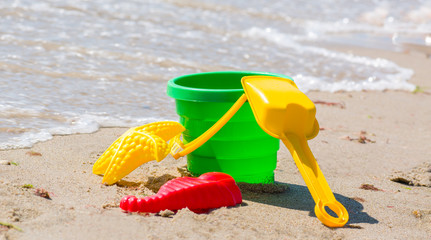 Toys for sand and water on the beach. Bucket and pasterns with a shovel on the seashore