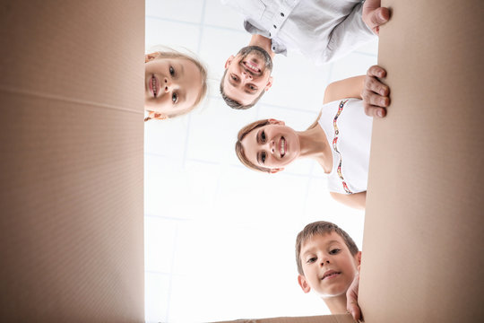 Happy Family Looking Inside Cardboard Box. Move House Concept