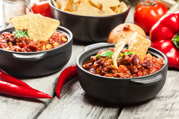 Bowls of hot chili con carne with ground beef, beans, tomatoes and corn