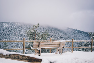 Wooden bench in snowy area.