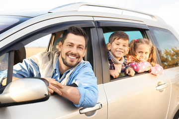 Young man with children in car, outdoors