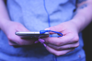 The girl adjusts the music before training. Headphones, phone.