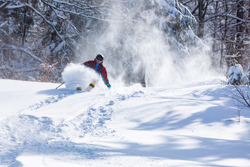 A skier is riding downhill in the deep snow.