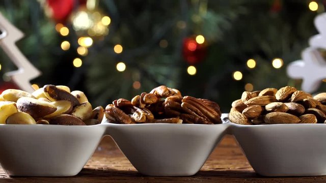 Walnut kernels cashew nuts and pistachions in a bowl on the board with blurred christmas background 