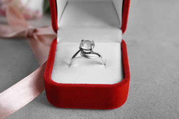 Box with luxury engagement ring on grey background, closeup