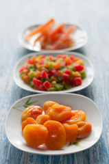 Different candied fruits in plates on a wooden table