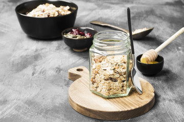 Granola with honey, nuts, fruit on a dark background. Copy space. Food background