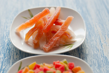 Candied papaya in a white plate on a wooden background