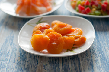 Candied dried apricots in a white dish on a wooden background with space for text