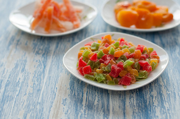 Candied pineapple cubes in a white dish on a wooden table