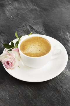 Espresso coffee in a white cup and a pink rose on a dark background