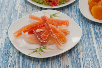 Candied papaya in a white dish on a wooden table