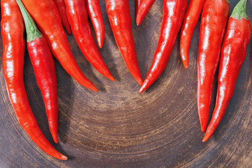 Red hot chili peppers on brown clay plate. Copy space. Close up fresh spicy peppers. View from above.