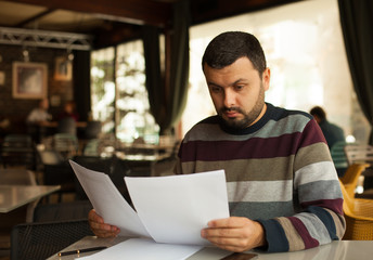 Stressed young man reading a document