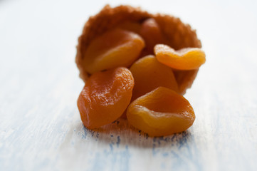 Creative minimal still life on blue colored background. Waffle cone with dried apricots . Copy space for text