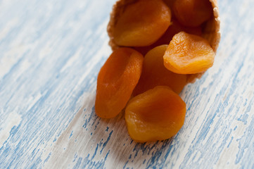 Creative minimal still life on blue colored background. Waffle cone with dried apricots . Copy space for text