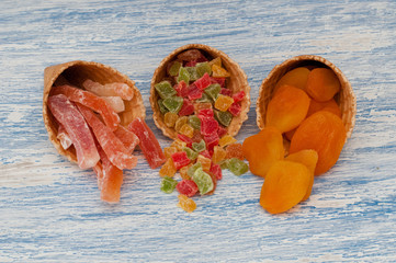 sweet candied fruit in a waffle cone on a wooden background