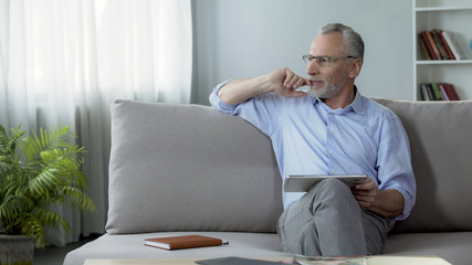 Adult person sitting on couch and booking a hotel room for vacation on tablet