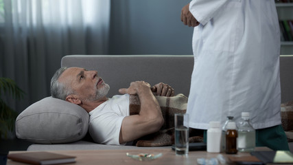 Grandfather lying on couch and complaining doctor of heart pain, healthcare