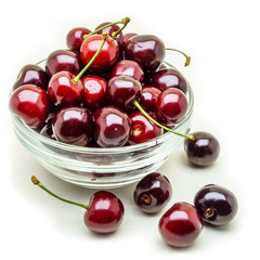 Glass vase with fresh wet cherries isolated on white background.