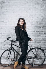 Fototapeta na wymiar Beautiful girl standing with a retro bicycle near a white brick wall