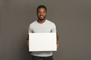 Picture of young african-american man holding white blank board