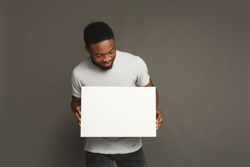 Picture of young african-american man holding white blank board - Powered by Adobe