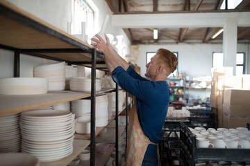 Male potter placing vase on shelf