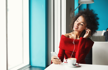 Fototapeta premium Happy balck girl at cafe listening to music