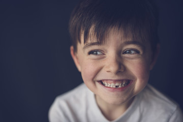 Close-up of cheerful boy clenching teeth while looking through sideways glance