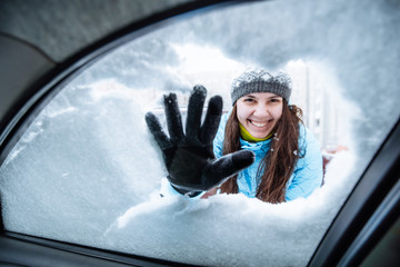 young woman clean car of snow