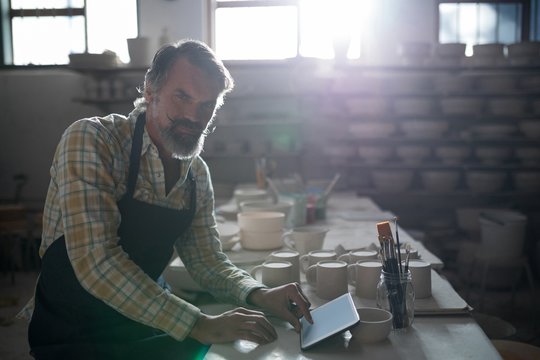 Portrait of male potter using digital tablet