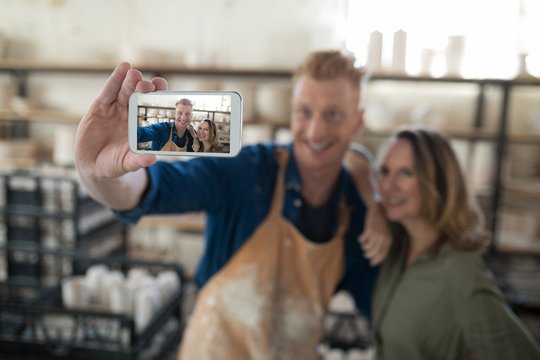 Male and female potter taking selfie with mobile phone