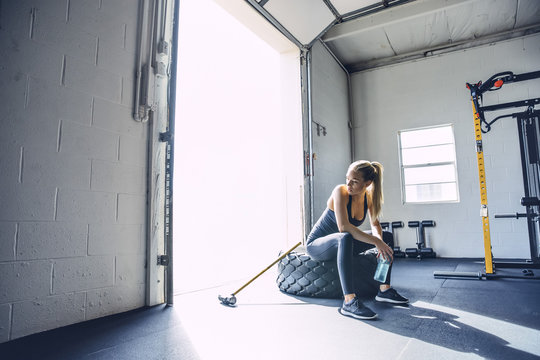 Young Woman Relaxing On Tire After Exercise