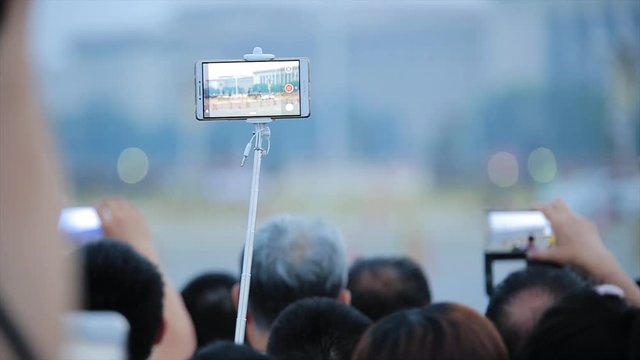 Tourists takes pictures with a smart phone, a famous landmark and a popular tourist attraction in China, view from back. Hands of people take photos on the street