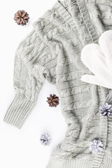 Soft, warm, cozy cardigan, scarf and mittens with fir cones on white background. Winter fashion concept